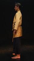 ein asiatisch Mann tragen ein traditionell Kostüm mit schön Motive auf seine Hemd und tragen ein Bandana namens ein Bendo im ein Zimmer foto