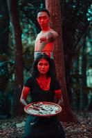 ein Paar von seriell Mörder haben Körper bedeckt im Blut und sind durchführen ein satanisch Ritual im das Mitte von ein Wald foto