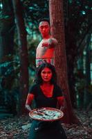 ein Paar von seriell Mörder haben Körper bedeckt im Blut und sind durchführen ein satanisch Ritual im das Mitte von ein Wald foto
