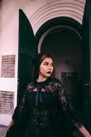 ein Hexe im ein alle schwarz Kleid und unheimlich bilden war Stehen beim das Friedhof Tor foto