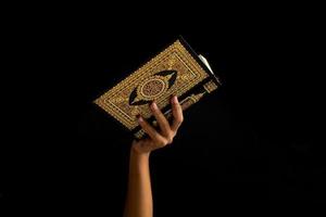 Hände halten heilig Koran im schwarz Hintergrund foto