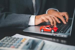 Nahansicht von ein klein rot Auto auf Laptop Tastenfeld. Planung zu verwalten Transport Finanzen Kosten. Konzept von Auto Versicherung Geschäft, Speichern Kaufen mit MwSt und Darlehen zum Neu Wagen. foto