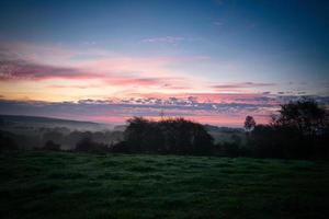 Sonnenaufgang Über ein benachbart Wald mit Wiese im das Vordergrund. Weide Landschaft foto