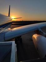 Vertikale Bild, Silhouette von ein Passagier Flugzeug Landung auf das Flughafen Schürze gegen das Hintergrund von das malerisch Orange Sonnenuntergang Himmel foto