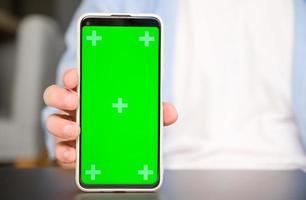 Nahansicht Attrappe, Lehrmodell, Simulation Bild von ein Mann halten und Smartphone zeigen mit Grün Chroma Bildschirm foto