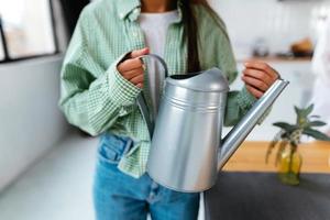 Frau hält ein Bewässerung können im ihr Hände beim Zuhause foto