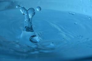 Spritzen Sie mit Wassertropfen mit blauem Hintergrund foto