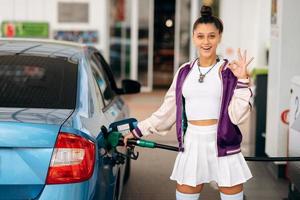 Frau, die ihr Auto an einer Tankstelle mit Kraftstoff befüllt foto