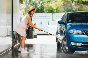 Brünette aus einem Hochdruckschlauch wäscht das Auto foto