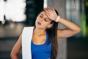 gesunde junge frau entspannt nach dem training im fitnessstudio. foto