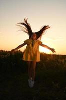 ein glücklich jung Mädchen mit lange Haar im ein Stroh Hut steht im ein groß Feld von Sonnenblumen. Sommer- Tag. ein warm Sonnenuntergang. foto
