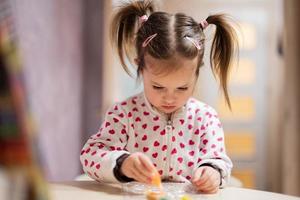 Baby Mädchen mit Zöpfe dekorieren Kunst mit funkeln Dekor Tube von malen. foto