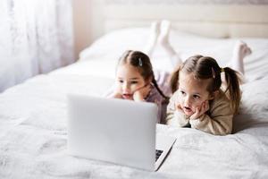 zwei Mädchen Schwestern Aufpassen auf Laptop. Technologie und Zuhause Konzept. foto