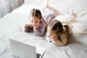 zwei Mädchen Schwestern Aufpassen auf Laptop. Technologie und Zuhause Konzept. foto