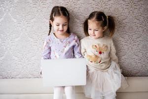 zwei Mädchen Schwestern Aufpassen auf Laptop. Technologie und Zuhause Konzept. foto