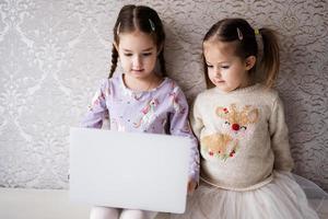 zwei Mädchen Schwestern Aufpassen auf Laptop. Technologie und Zuhause Konzept. foto