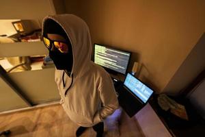 Junge Hacker. Internet Diebstahl . Mann tragen ein Sturmhaube hinter ein Laptop. foto