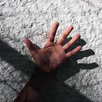 Hand auf das Weiß Mauer spielen mit das Schatten foto