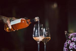 Mann Gießen Rose Wein von Flasche in Glas drinnen. foto