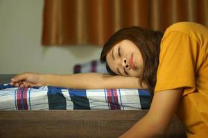 asiatisch Frau Schlafen auf das Bett fällig zu schwer Arbeit foto