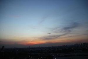 dunkel Blau Wolke mit Weiß Licht Sonne einstellen Himmel Hintergrund und Stadt Licht Mitternacht Abend Zeit foto