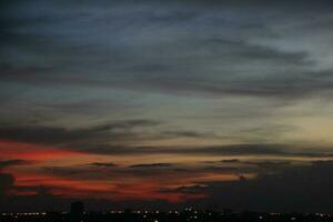 dunkel Blau Wolke mit Weiß Licht Sonnenuntergang Himmel Hintergrund und Stadt Licht Mitternacht Abend Zeit foto