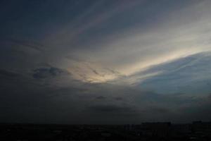 dunkel Blau Wolke mit Weiß Licht Sonne einstellen Himmel Hintergrund und Stadt Licht Mitternacht Abend Zeit foto