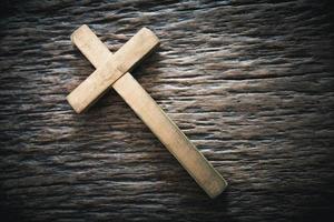 ein hölzern Christian Kreuz Kruzifix auf ein Grunge Tafel Hintergrund. hölzern Christian Kreuz auf grau Tabelle gegen verschwommen Beleuchtung, Raum zum Text. foto