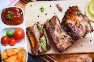 Grill Schweinefleisch Rippen gegrillt mit Tomaten Ketchup und Kräuter Gewürze serviert auf das hölzern Schneiden Tafel auf Tabelle - - geröstet Grill Schweinefleisch schonen Rippe geschnitten foto