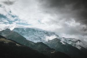 majestätisch Berge im das Alpen bedeckt mit Bäume und Wolken foto