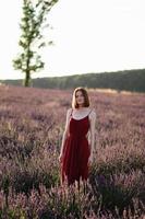 ein rothaarig jung Mädchen ohne bilden ist ruhen im ein Lavendel Feld. Sommer- Ferien und Reise Zeit. foto