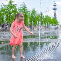 wenig Mädchen spielen auf ein Wasser Brunnen foto