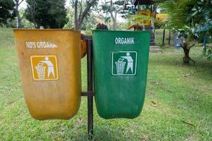 Fokus Fokus auf das zwei Gelb und Grün Müll Büchsen, Grün zum recycelbar Abfall, Gelb nicht recycelbar Müll im das Erholung Park Bereich, Sanft Fokus foto