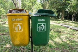 Fokus Fokus auf das zwei Gelb und Grün Müll Büchsen, Grün zum recycelbar Abfall, Gelb nicht recycelbar Müll im das Erholung Park Bereich, Sanft Fokus foto