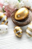 Nest mit Ostern Eier gemalt golden Farben auf ein Weiß hölzern Hintergrund. foto