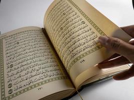 lesen al Koran und drehen Seite von Koran über Sajada beten Matte isoliert auf Weiß Raum. ausgewählt Fokus foto