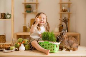 süß wenig Mädchen im das hölzern Küche von das Haus Einspeisungen das Hase frisch Gras foto