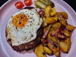 Hacksteak ein la Meier Beefsteak mit gebraten Eier und geröstet Kartoffeln foto