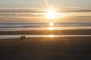 Strand im Orange Sonnenschein beim Sonnenuntergang foto