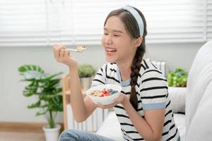 gesund Lebensmittel. schön weiblich Mädchen genießen Essen Joghurt, Granola, frisch Früchte auf Frühstück Gesundheit im Haus. glücklich jung Frau Lächeln auf Morgen gut Emotion. Diät, Entgiftung, Diät, sauber essen, Vegetarier foto