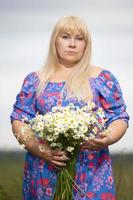 schön Plus Größe Frau mit Weiß Haar im ein Sommer- Kleid posieren draußen mit Gänseblümchen. mollig Mädchen im ein Wiese mit Blumen. foto