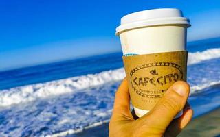 puerto escondido Oaxaca Mexiko 2023 Kaffee zu gehen Becher auf das Strand Sand Meer Wellen. foto