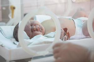 ein neugeborenes baby liegt in boxen im krankenhaus. ein Kind in einem Inkubator. Neugeborenen- und Frühgeborenen-Intensivstation foto