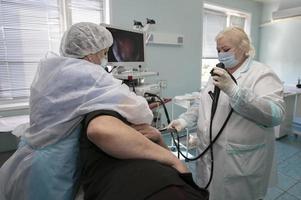 ein weiblich Arzt hält ein Endoskop während ein Gastroskopie zum ein Krankenhaus geduldig. medizinisch Büro zum Diagnose Bauch Schmerz. foto