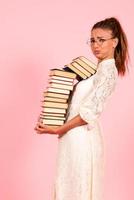 Rosa Hintergrund, Mädchen lesen Bücher, Buch Liebhaber, Schüler halten ein groß Stapel von Bücher foto