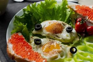 Frühstück, durcheinander Eier auf Grüner Salat Blätter, Nächster zu frisch Gemüse und ein Sandwich mit rot Kaviar foto