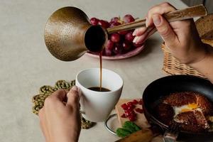 Mädchen isst Frühstück und gießt Kaffee von ein Türkisch foto