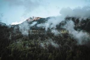 majestätisch Berge im das Alpen bedeckt mit Bäume und Wolken foto