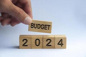 Hand halten hölzern Block mit Text - - Budget 2024 mit verschwommen Natur Hintergrund. jährlich Budget Konzept foto