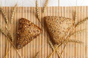 Brot und Weizen auf weißem Hintergrund aus Holz foto